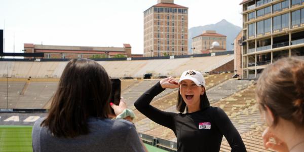 Student taking photo of another student in folsom field