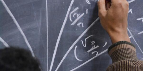 A student doing a math problem on a chalk board
