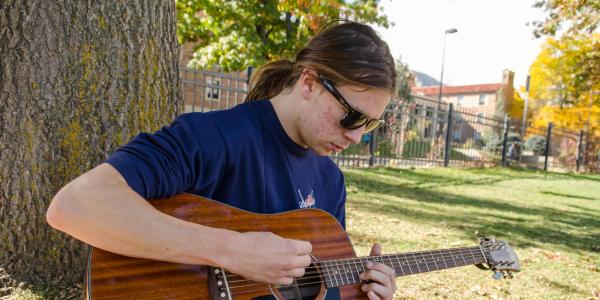 Student playing guitar in the quad