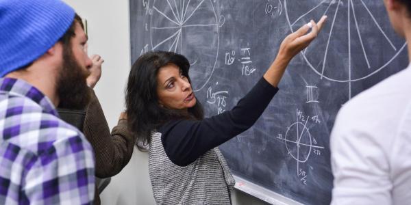 Professor working an applied math problem on chalkboard with students