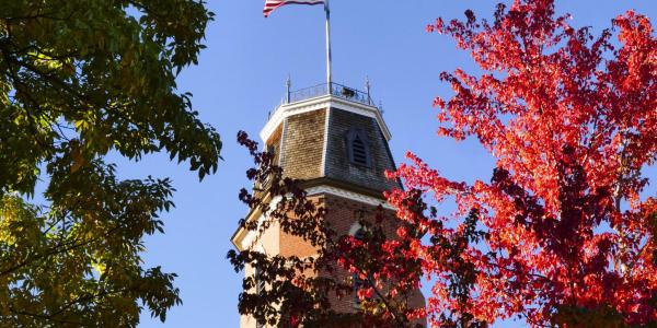 Top of Old Main building framed with fall leaves